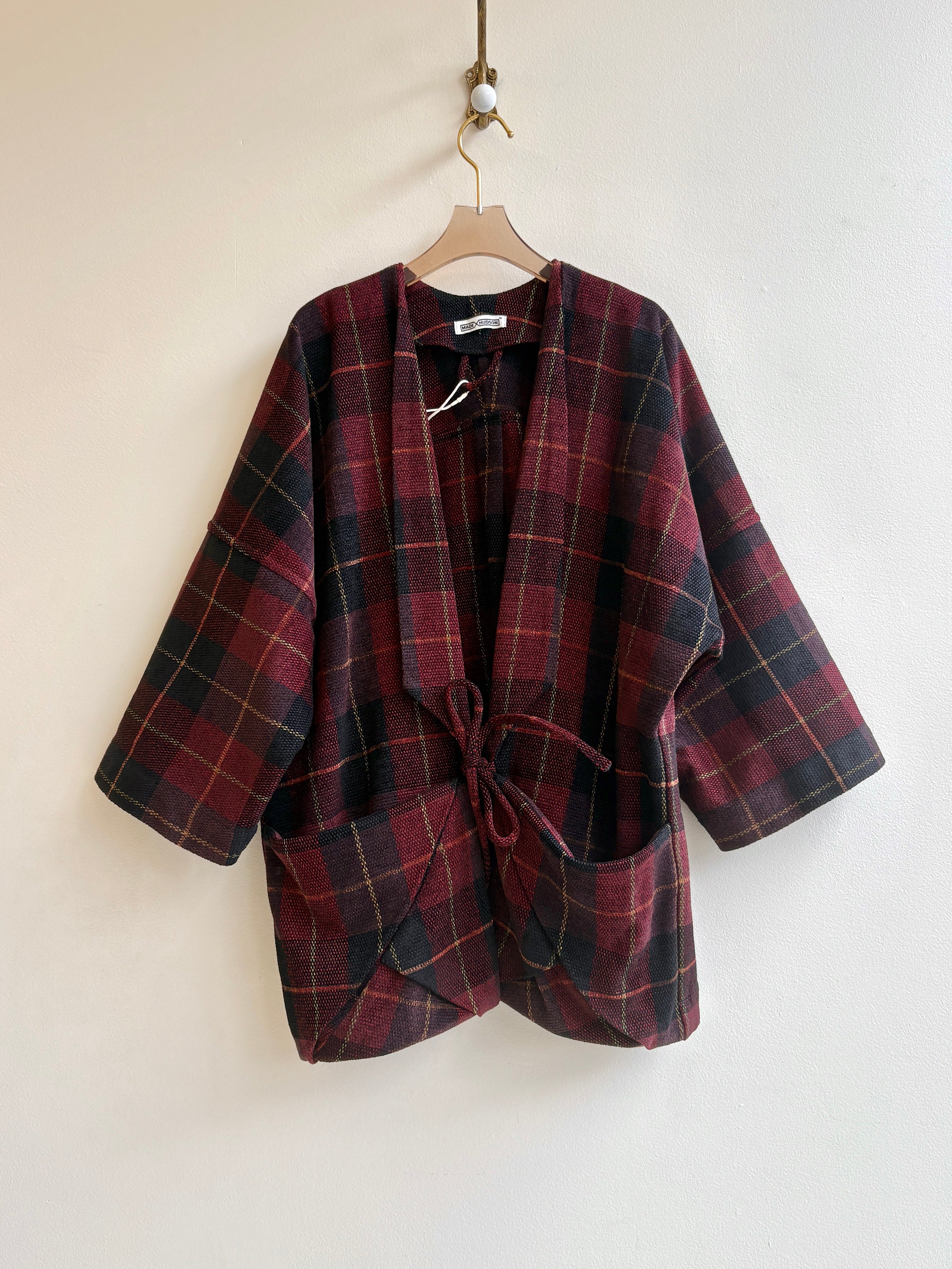 Plaid jacket on a hanger against a plain background