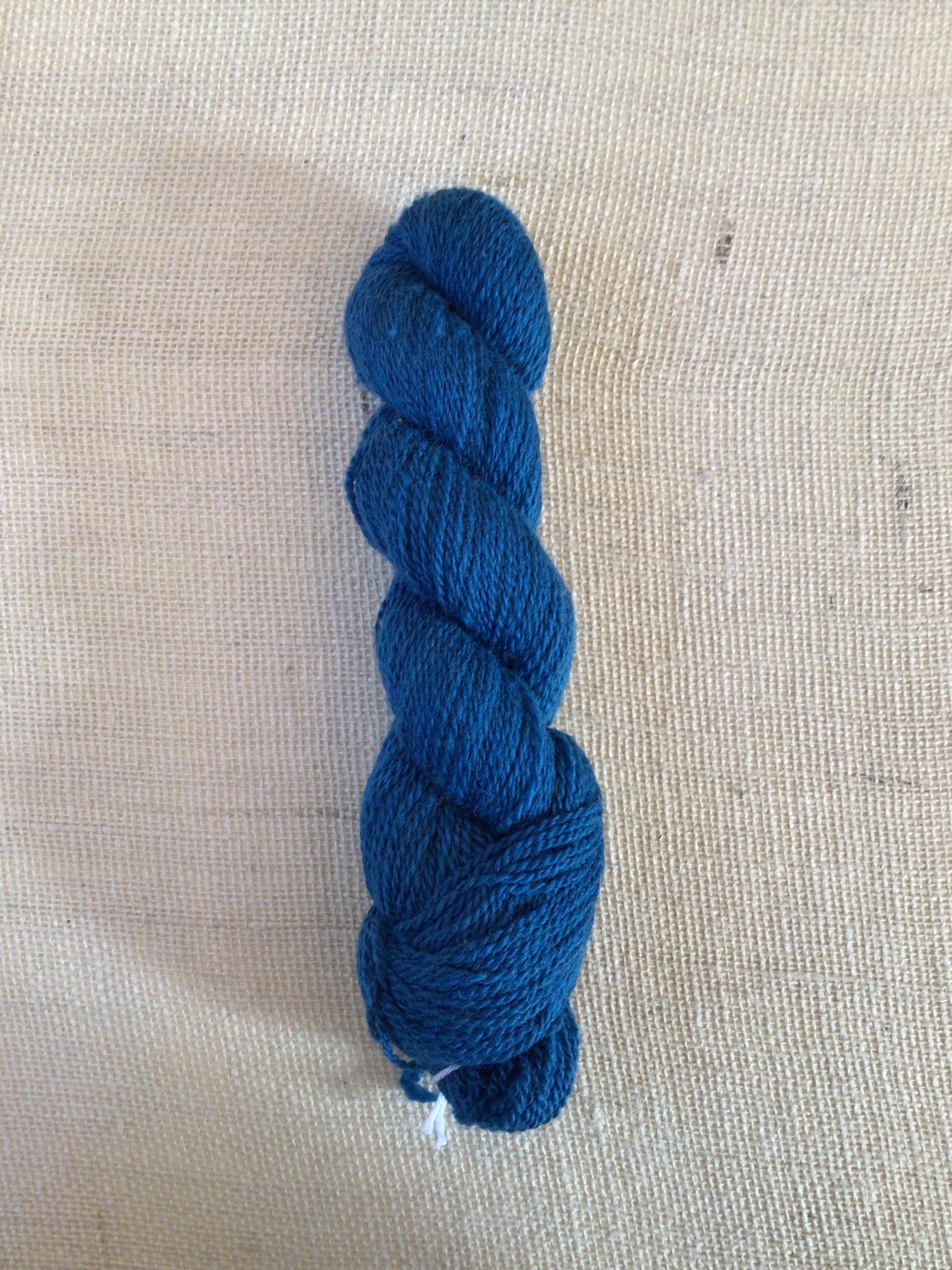 A skein of bright blue yarn sits on a neutral canvas background