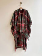 Plaid poncho with fringes on a hanger against a white background