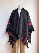Black poncho with red and gray stripes on a mannequin against a white background